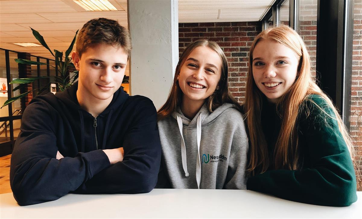 Tre elever sitter rundt et bord i skolens foaje - Klikk for stort bilde
